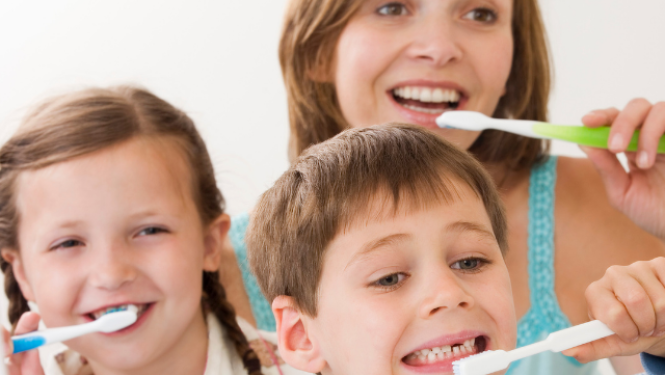 Bērni mājās tīra zobus kopā ar pieaugušo.