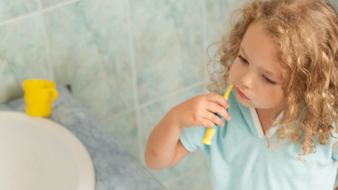 Mazs bērns vannasistabā tīra zobus pie izlietnes.