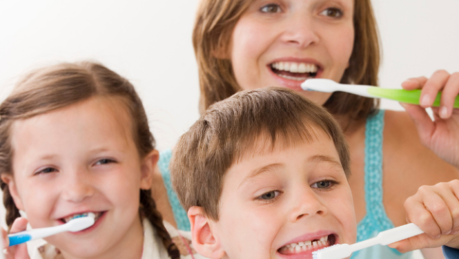 Bērni mājās tīra zobus kopā ar pieaugušo.