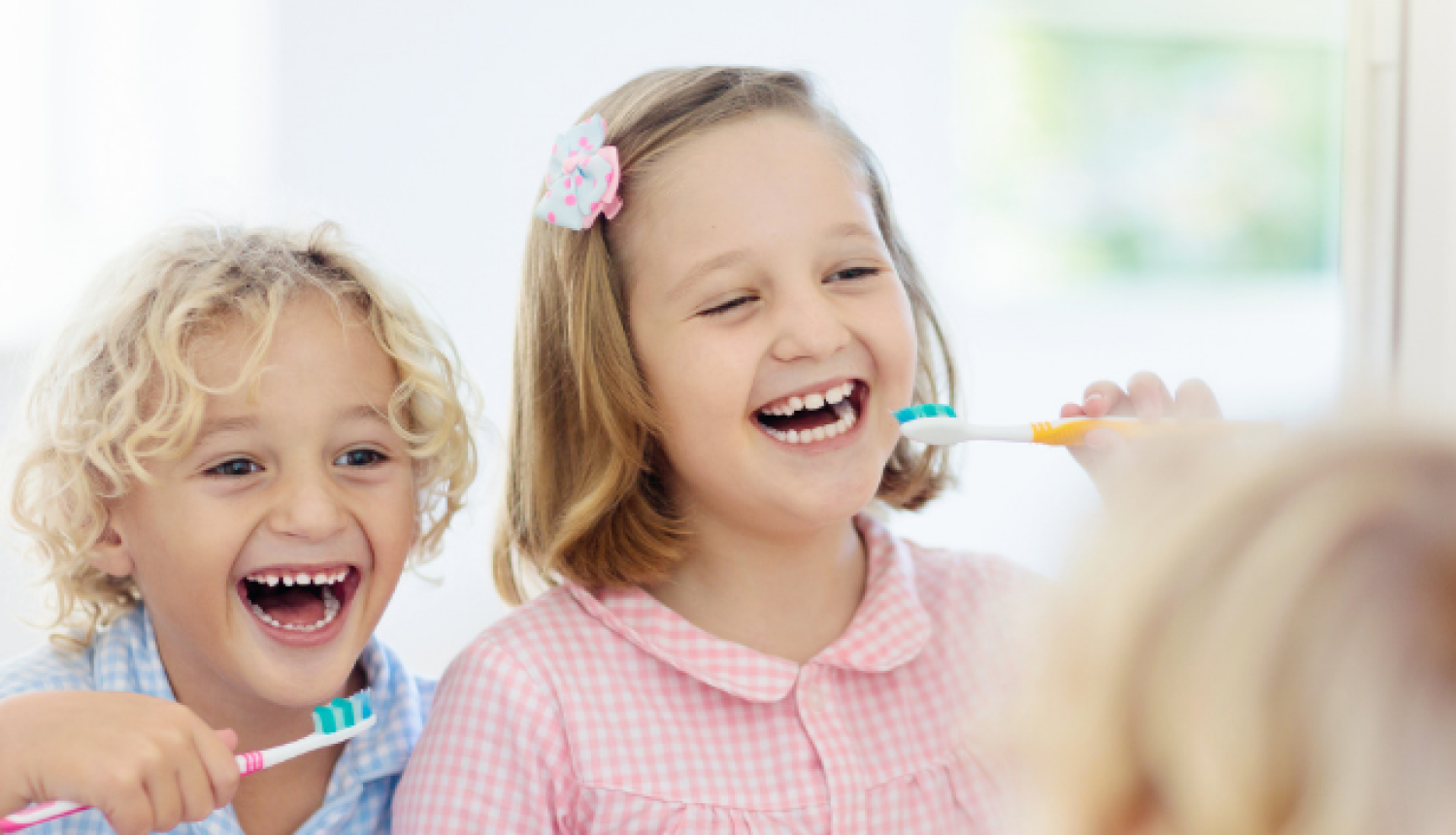 Bērni tīra zobus vannasistabā un skatās spogulī.