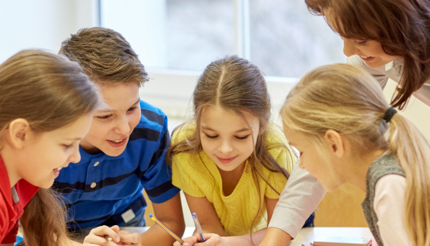 Skolēni strādā grupā pie galda, kopīgi pildot mācību uzdevumu.