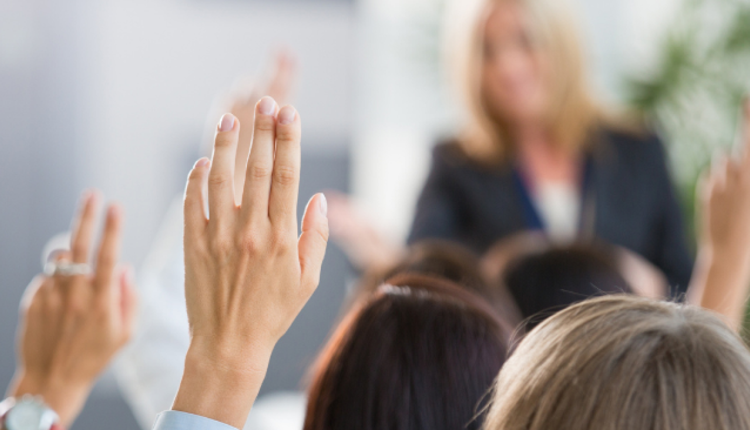 Skolēni paceļ rokas klasē, piedaloties mācību stundā.