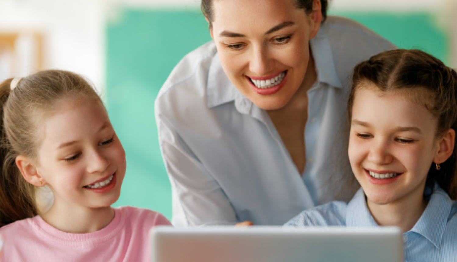 Skolotāja kopā ar bērniem skatās mācību saturu datorā.