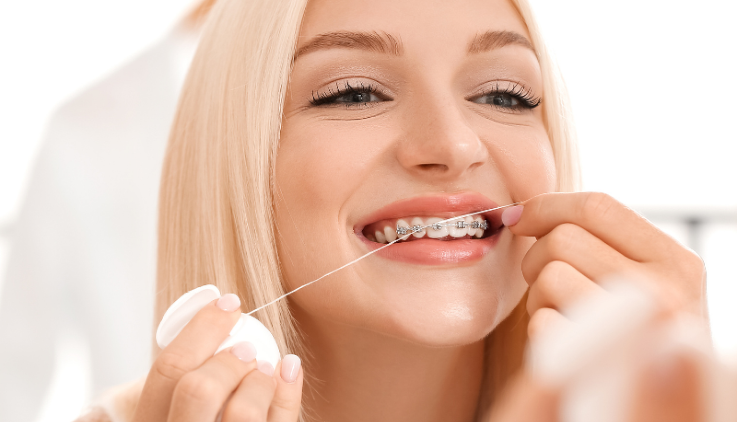 Sieviete ar breketēm lieto zobu diegu.