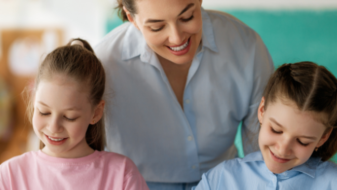 Skolotāja palīdz bērniem pildīt rakstīšanas uzdevumus pie galda.